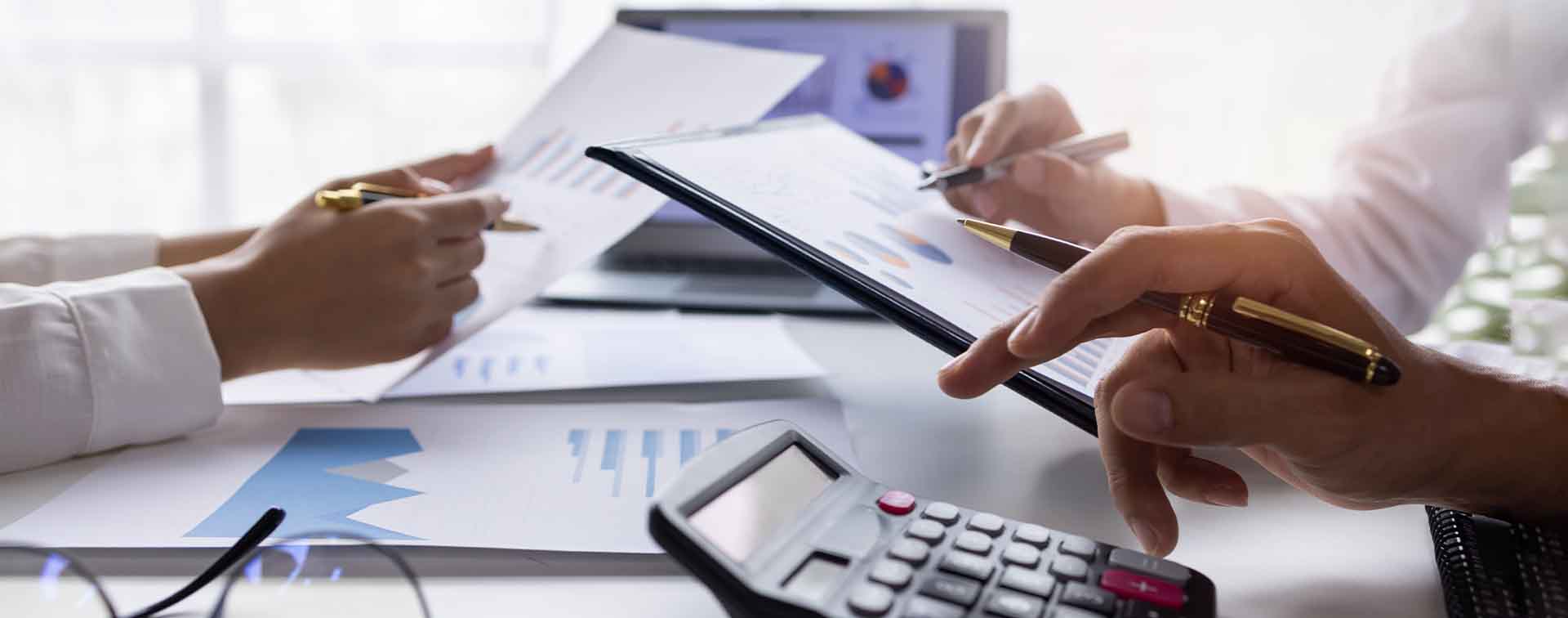 Close-up of financial experts analyzing charts as  one types on a calculator