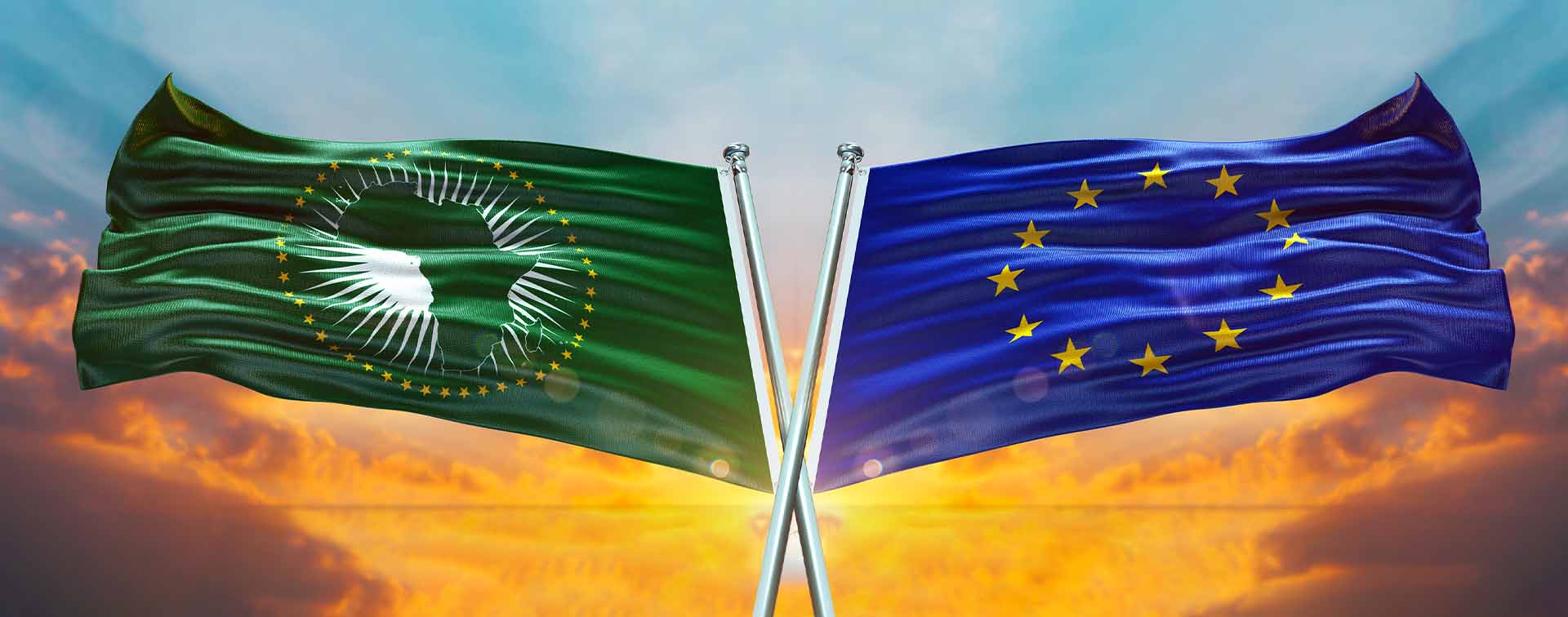 The waving UN flag crossed over the African Union flag in front of a sky at sunset.