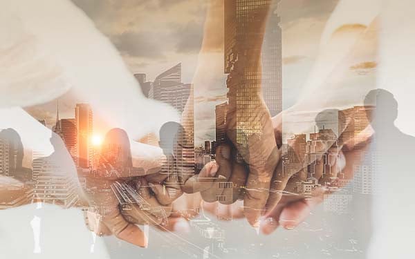 Digital composite of different-toned fists touching over the shadows of people standing beside each other looking at a skyline at sunset