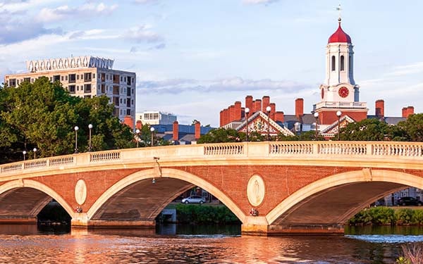 Arch bridge on the Harvard campus over the Charles River with a view of Boston behind it