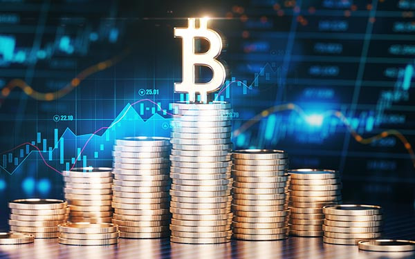 The Bitcoin Symbol on Top of Stacks of Coins in Front Of a Financial Chart