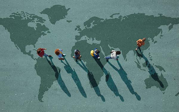 People walking in line across world map, painted on asphalt, front person walking left